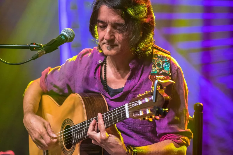 Manu en concierto con la guitarra, bajo luces moradas