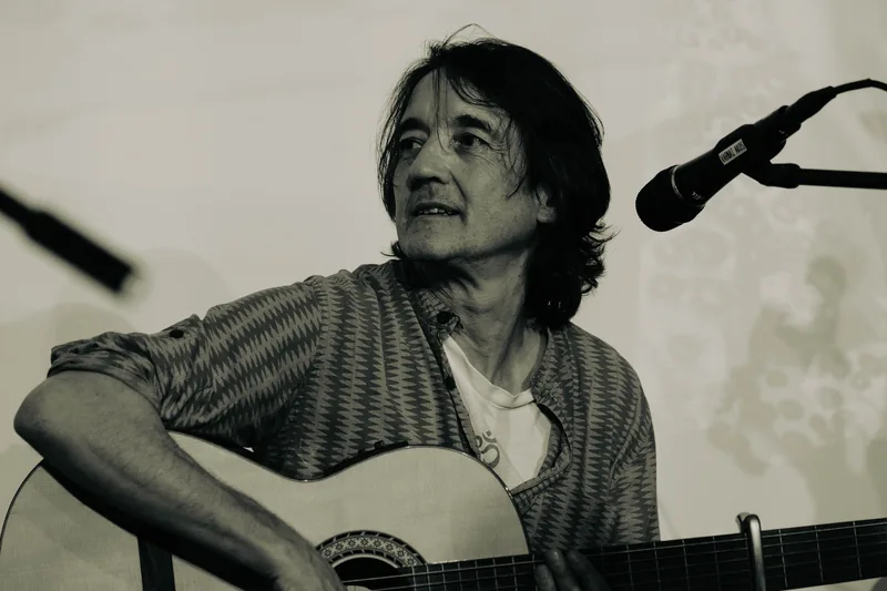 Manu cantando con la guitarra, en blanco y negro