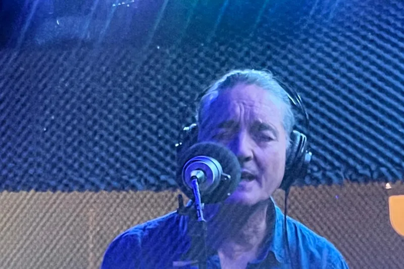 Manu cantando en el estudio, con auriculares, frente al micrófono